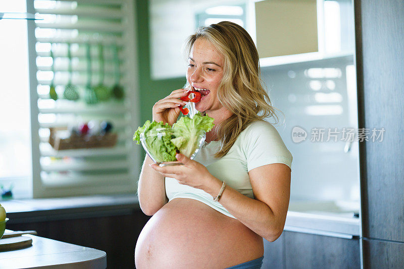 孕妇在厨房里吃蔬菜