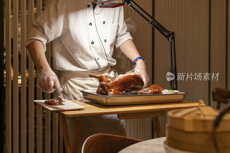 在餐馆的厨房里，厨师正在切美味的北京烤鸭