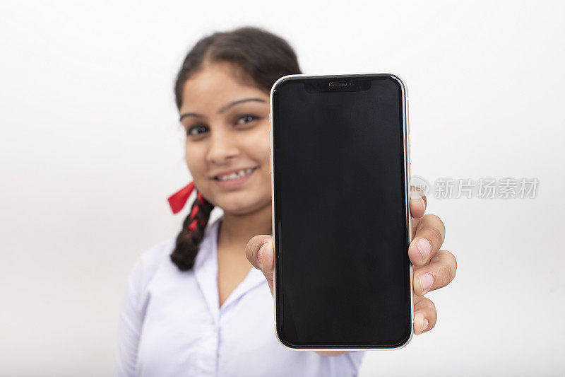 农村学校的女孩显示空白屏幕的手机库存照片