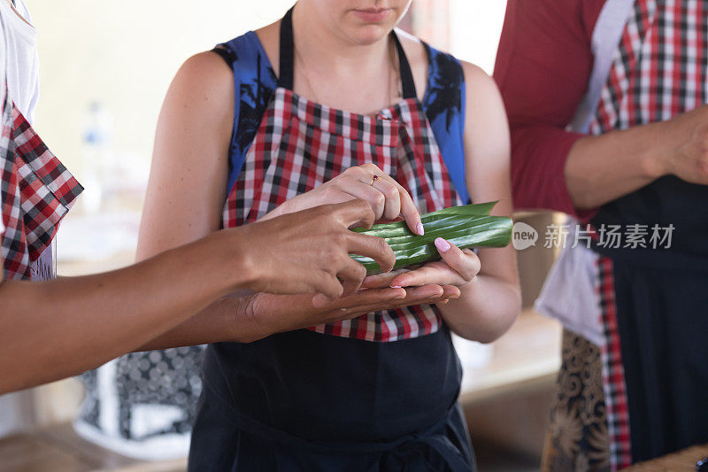 在印度尼西亚巴厘岛，一名妇女在参加一个烹饪课程时用香蕉叶包装食物