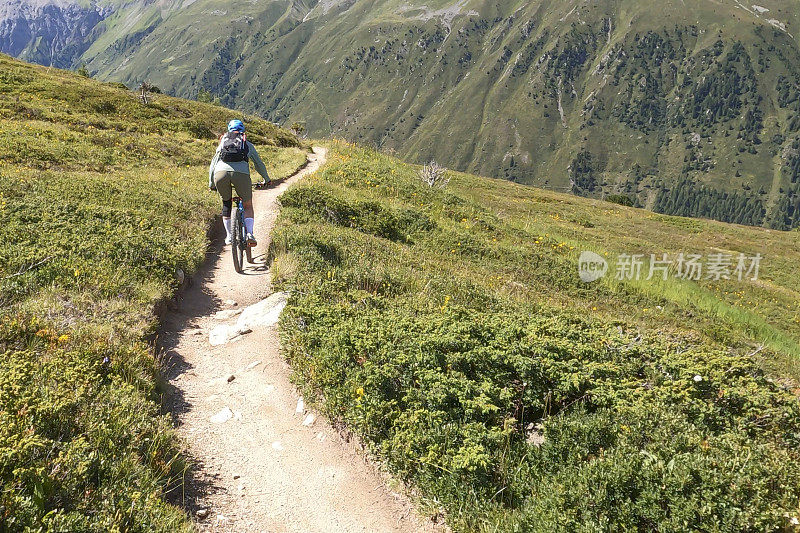 女人沿着阳光明媚的自行车道骑山地车