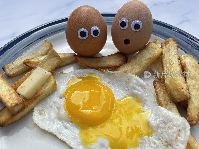 近景煎蛋，破黄的蛋黄渗，薯条坐在蓝边盘子旁边的两个有壳的鸡蛋与大眼睛，恐惧的卡通面孔，幽默的概念，大理石效果背景，上升的视野，聚焦前景
