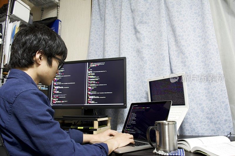 一个年轻的亚洲程序员在他的房间里编程