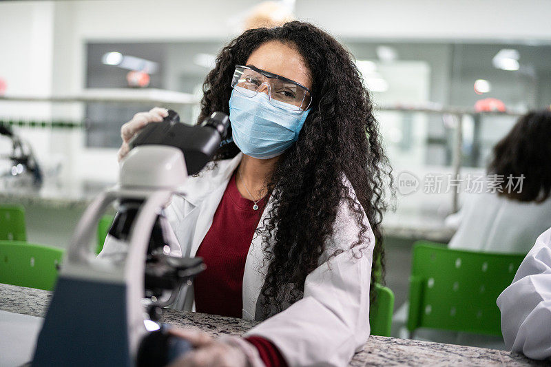 女学生在实验室使用显微镜的肖像-使用一个面罩