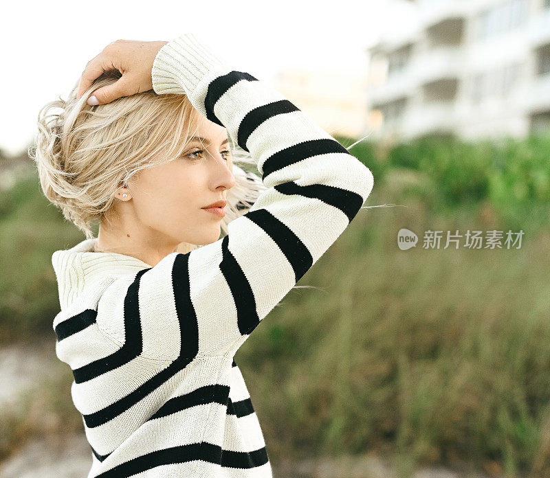 时尚的女人在海滩度假在航海风格的条纹毛衣在旅游胜地