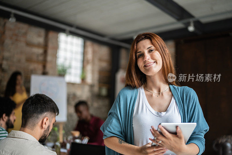 一名年轻的女商人在办公室里手持数码平板电脑的肖像