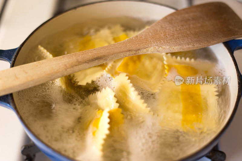 炉子上的沸腾馄饨锅，木头勺子在上面