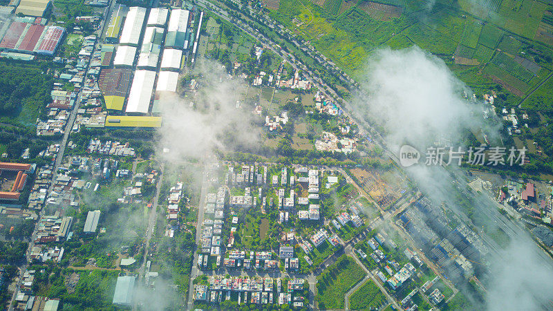 无人机查看小曲径街道和道路在一个小城镇的居民区附近的大城市在越南与云和天空。
