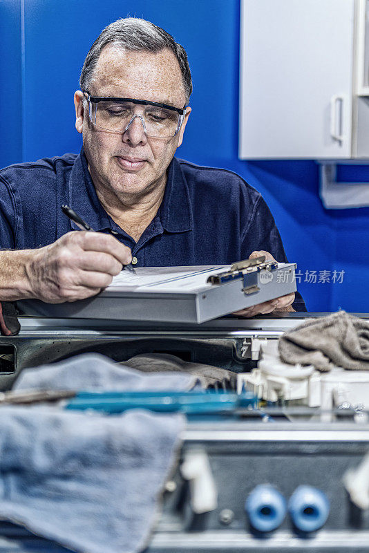 电器修理工在洗衣机上工作后写工作单