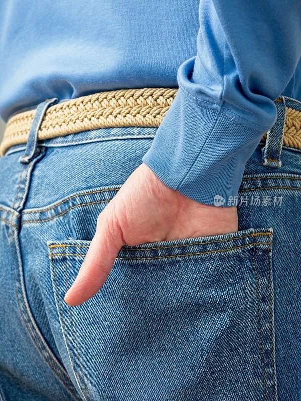 中年白人男子，拇指从牛仔裤口袋里伸出，穿着蓝色的衣服
