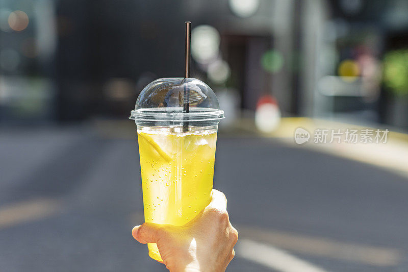 用塑料杯盛着柠檬水的女人的手