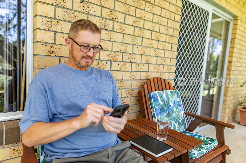 一个在家户外使用智能手机的成熟男人