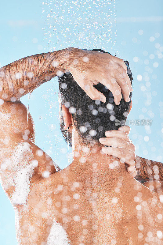 美容、清洁头发和男人在淋浴时用洗发水、护发素和护发产品清洗。卫生，仪容整洁和背部男性清洗身体自我护理，健康和皮肤护理在蓝色背景