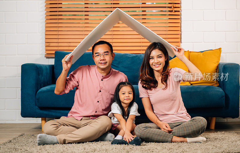 幸福的家庭拿着象征生命保险的纸板屋顶