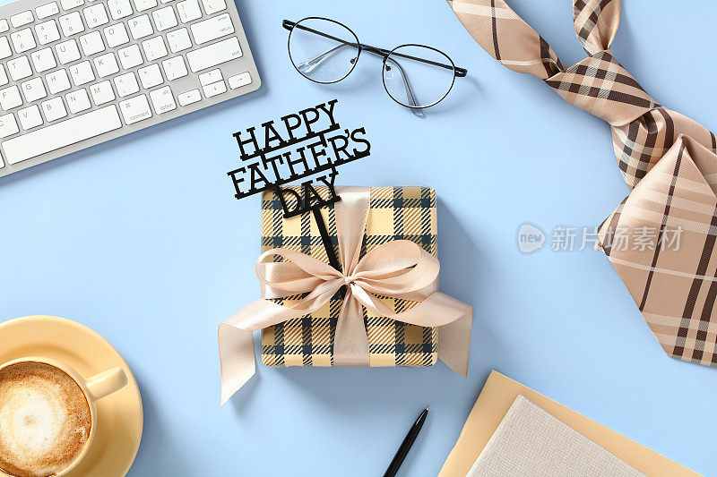 父亲节快乐的概念。带有父亲节快乐的老式礼盒，眼镜，领带，咖啡杯，键盘，蓝色背景的纸质笔记本。