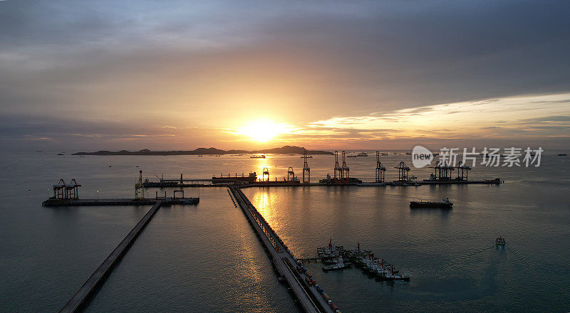 以美丽的夕阳为背景的港口，远处的港口在夕阳的映照下，天空映照着海港上的起重机，夕阳的天空五彩缤纷