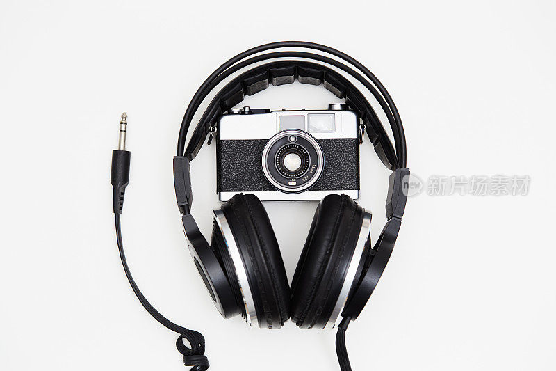 音乐和摄影。白色背景的单反胶片相机和音乐耳机