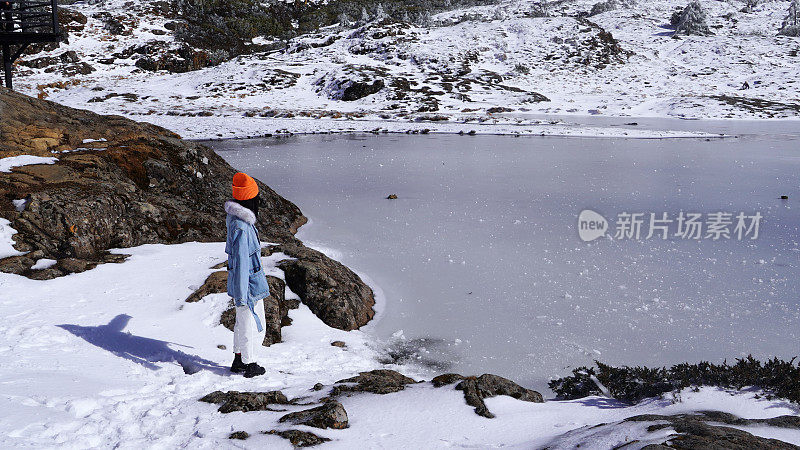 一个女人在寒冷的天气里穿行于白雪覆盖的山林之中