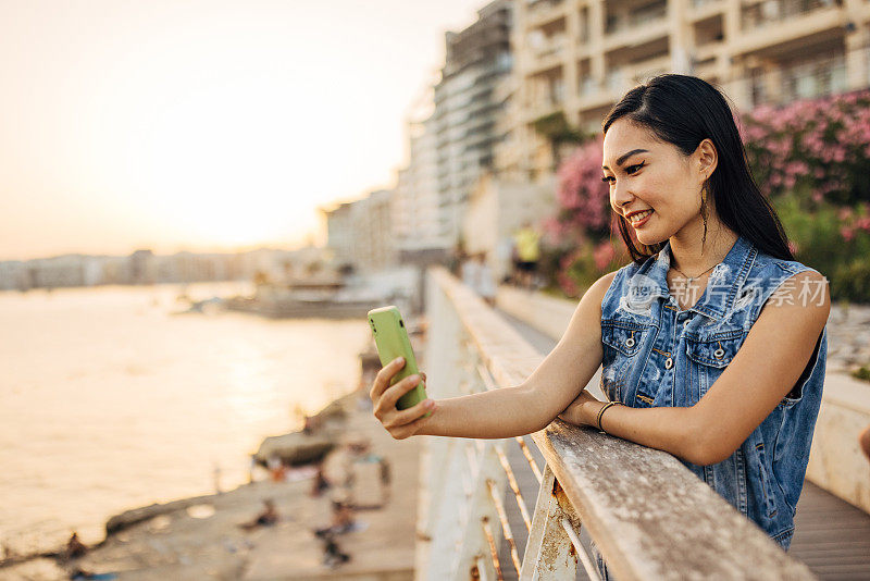 一位微笑的亚洲妇女用手机拍摄马耳他首都的美景