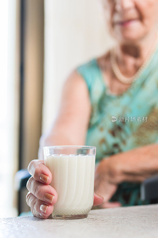 一个面目全非的老妇人拿着一杯牛奶