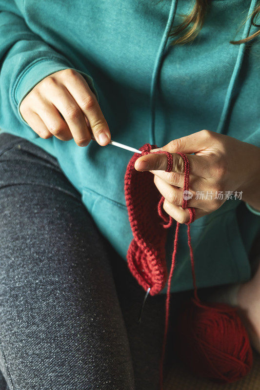 一个年轻的白人妇女用红纱织围巾的特写镜头。坐在客厅的沙发上