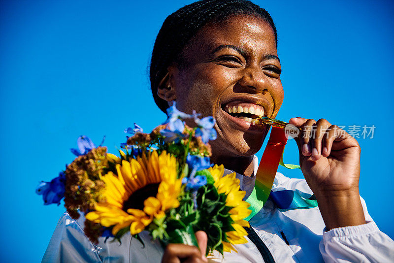 国际运动员手持奖牌和花束。户外肖像蓝色背景。对成功理念的反思