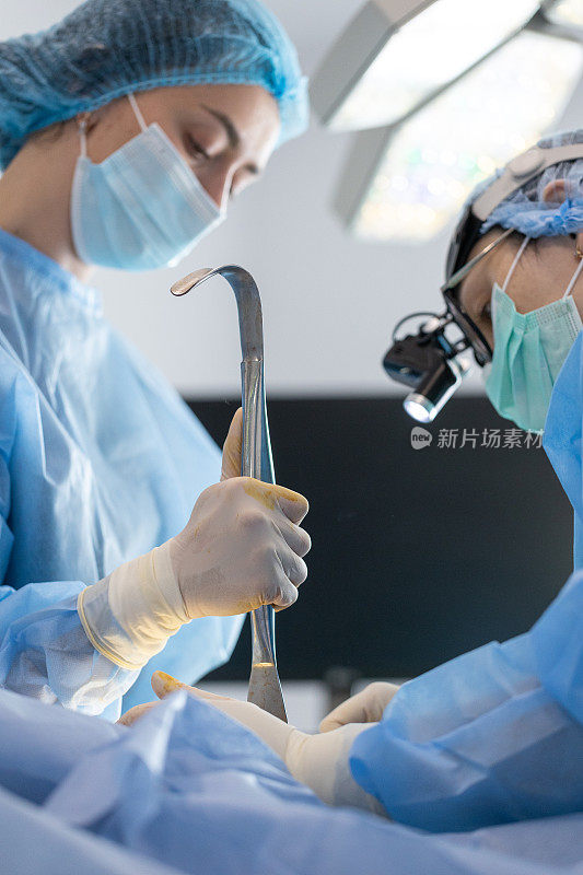 整形外科医生和手术室护士在一个女人的乳房上做手术。