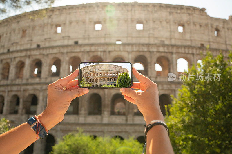 在意大利罗马的斗兽场圆形剧场，一名妇女用智能手机拍照