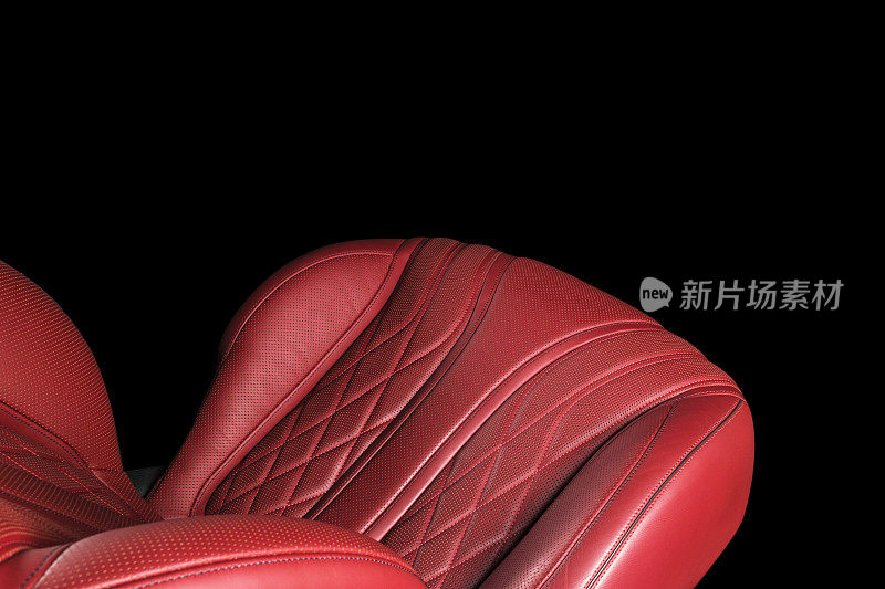 汽车内部的红色皮革。穿孔皮革舒适座椅与缝线隔离在黑色背景。汽车内饰的细节。汽车详细。汽车内部