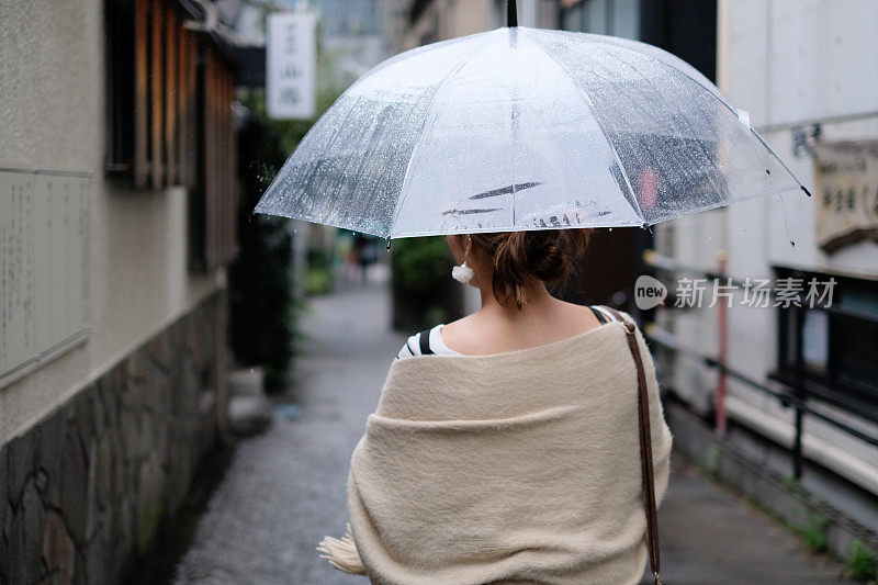 在一个雨天，在东京神乐坂传统老城的小巷里走着的女人的背影