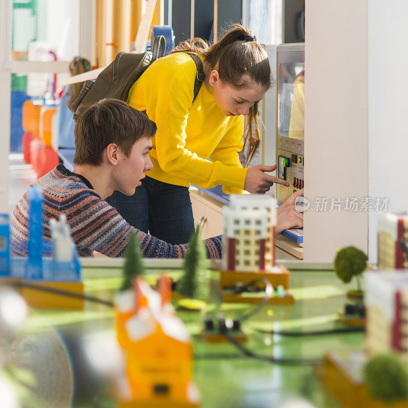 青少年，男孩和女孩，在科学技术馆的展览中探索电子设备