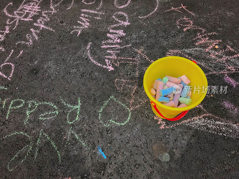 黄色的桶装满了粉笔在街道上用粉笔写的字和标志