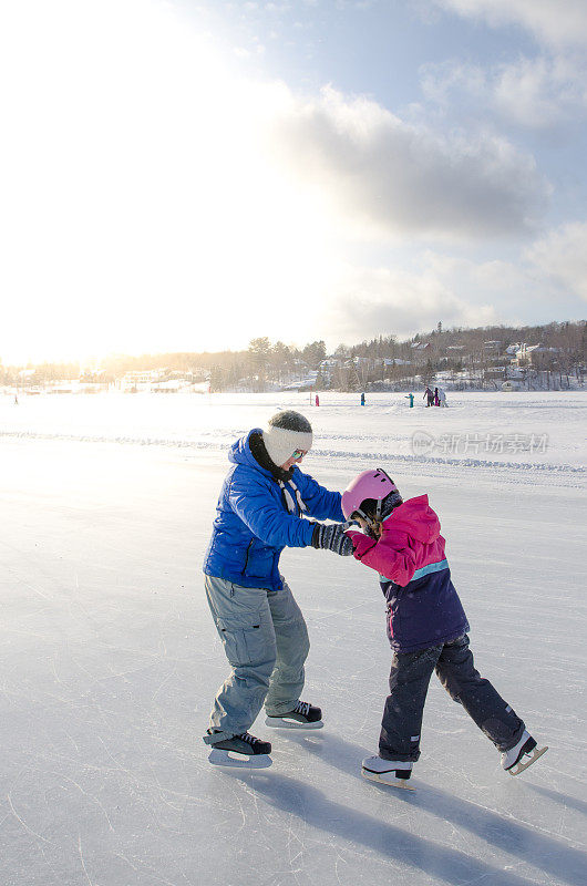 冬天，母亲和女儿在湖上的溜冰场溜冰