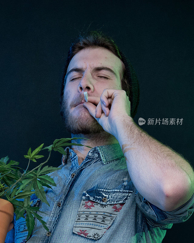 年轻的瘾君子和大麻植物站在一起