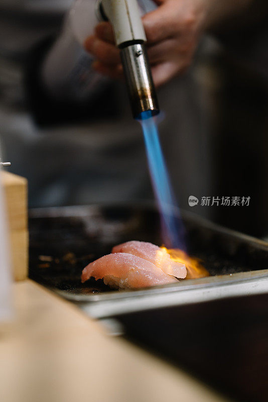 寿司师傅用喷灯准备寿司的特写镜头