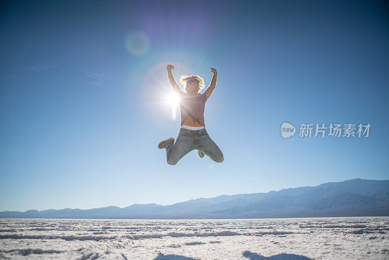 快乐的男人在盐滩中间跳得很高，男人高兴地跳着去旅行