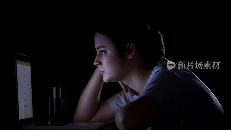 女孩自由职业者工作在笔记本电脑深夜，看起来疲倦和困倦