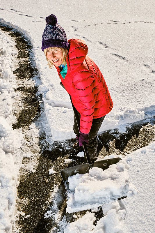 老妇人正在用雪铲清理前院的积雪