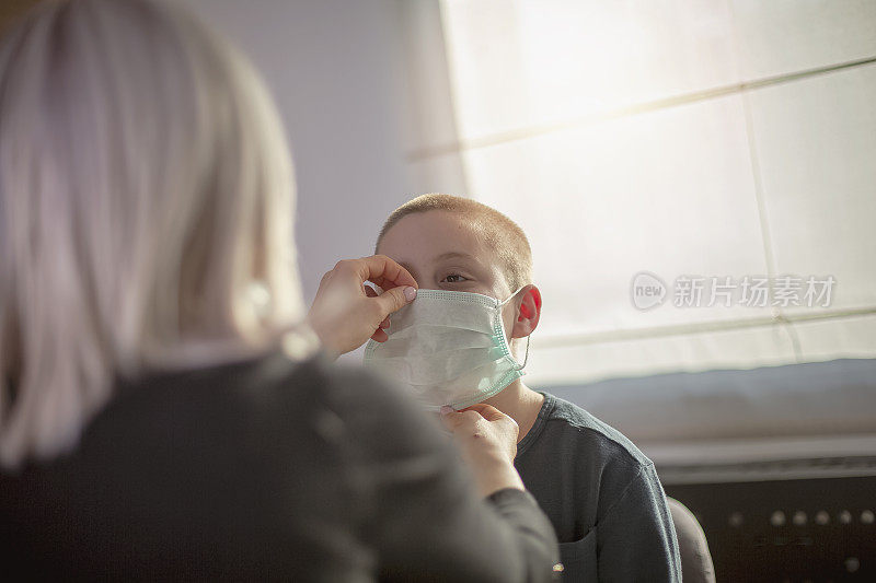 母亲和她的儿子戴上口罩保护自己免受病毒感染