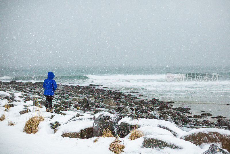 俯瞰挪威罗浮敦白雪覆盖的海滩的女人。