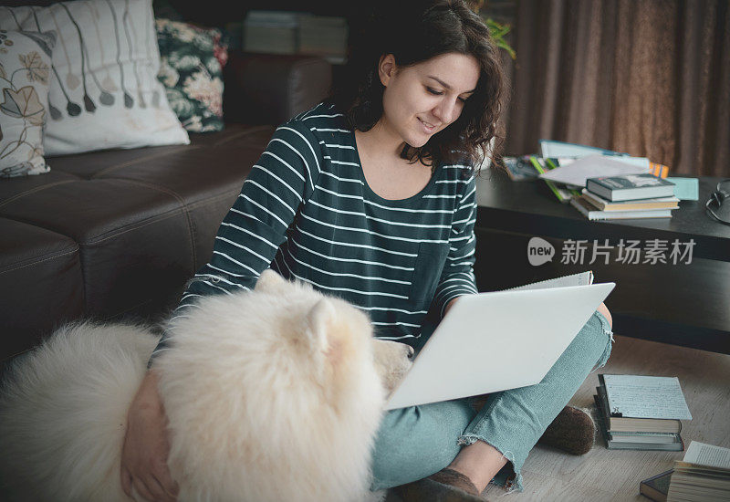 漂亮的年轻女人在家里工作与狗