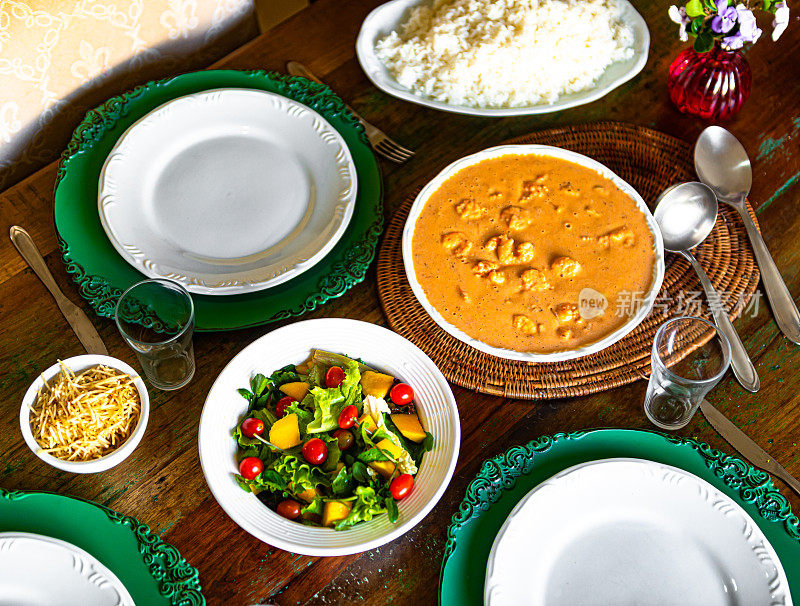 俄式鲜虾，配上白米饭、绿色沙拉、芒果和樱桃番茄，放在一张质朴的桌子上