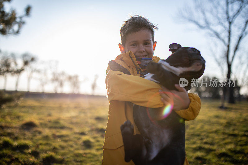 一个快乐可爱的男孩抱着一只法国斗牛犬