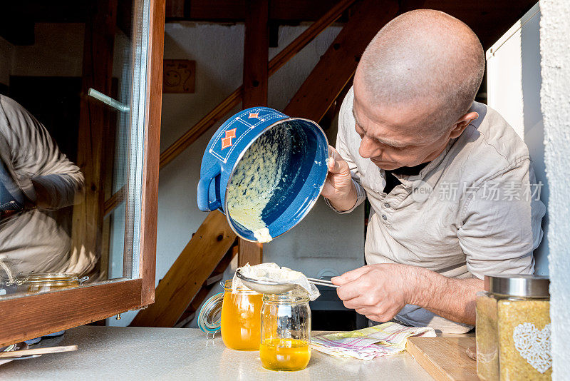 一名男子将融化的黄油倒入玻璃罐中，获得完美的酥油