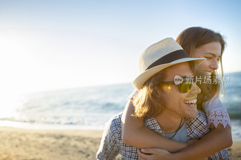 情侣们在日落或日出时在海滩上玩背包游戏。