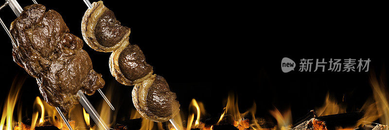 Picanha和ancho牛排肉在烤架上与火。巴西烧烤。