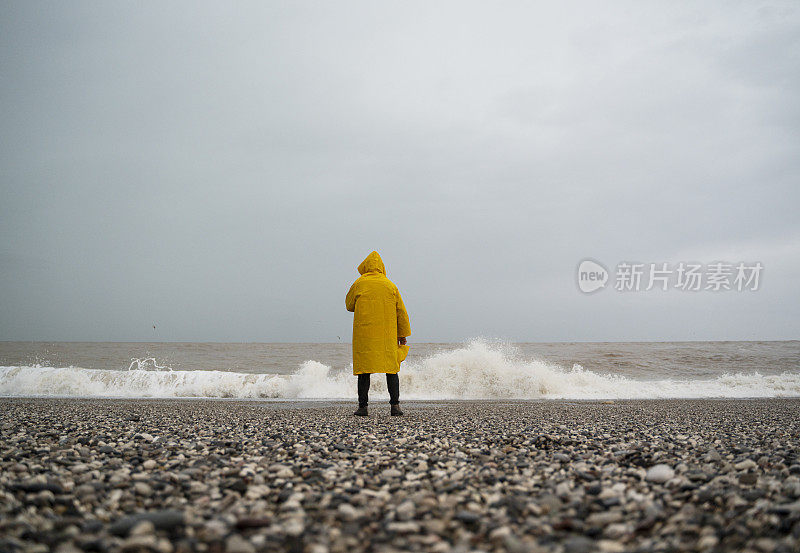 土耳其安塔利亚，一个下雨天，一名身穿黄色雨衣的男子在海滩上