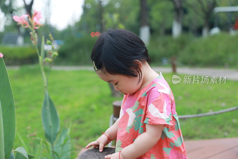 一个中国小女孩在人行道上玩耍，她抓着扶手往下看