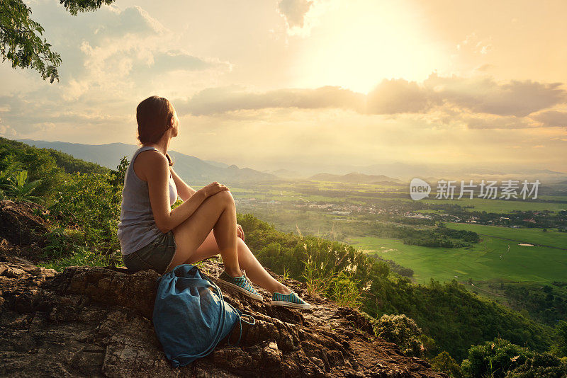 女孩坐在悬崖边，看着太阳谷