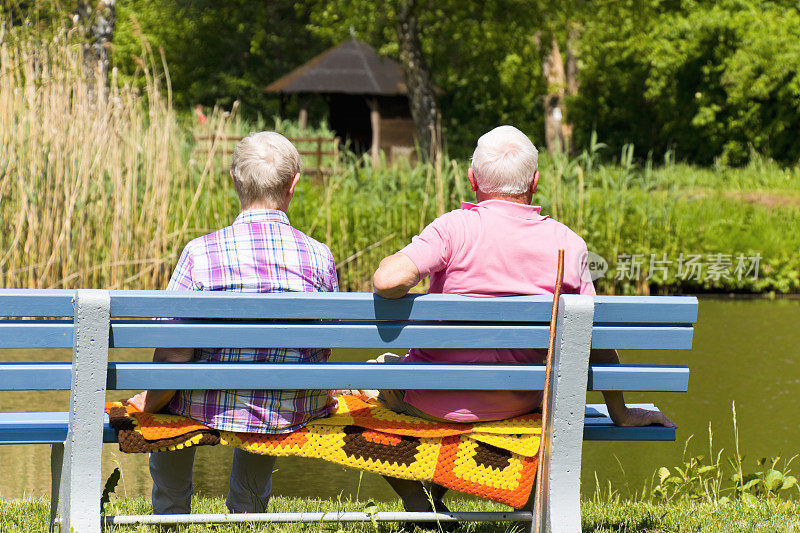 一对退休夫妇坐在森林湖边